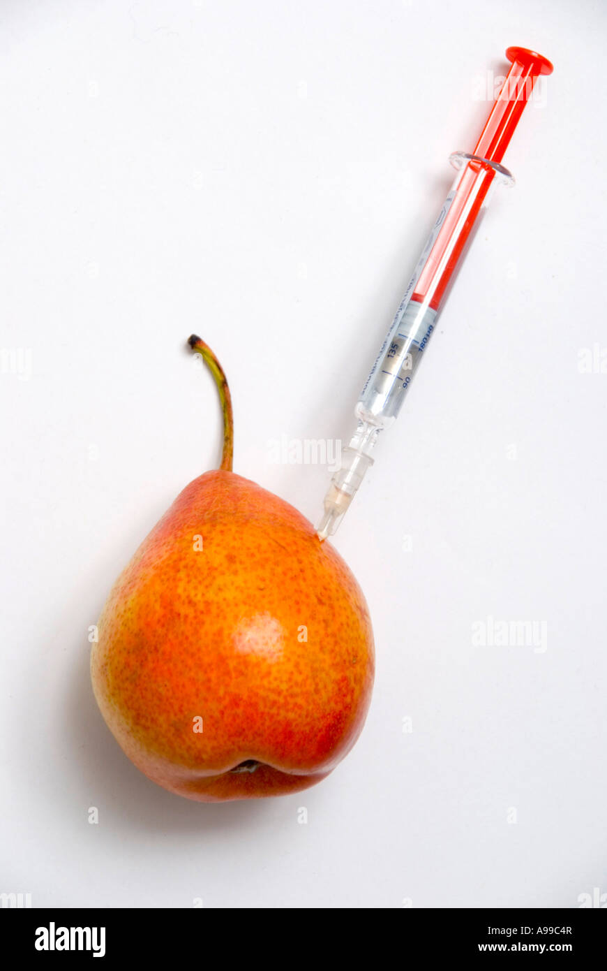 A pear with a hypodermic syringe illustrate the concept of genetically modified food Stock Photo
