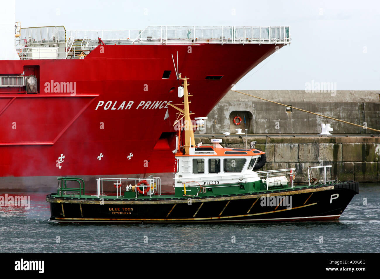Pilot boat 'Blue Toon' escorts an oil supply vessel out of Peterhead harbour, Scotland, UK. Stock Photo