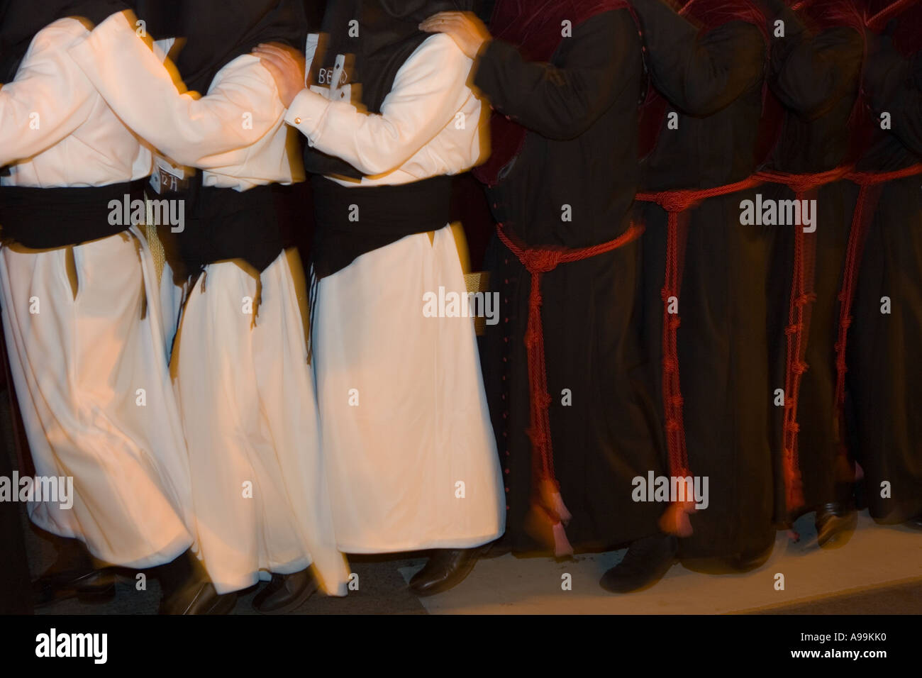 Hooded members of a religious fraternity wearing robes carry a float ...