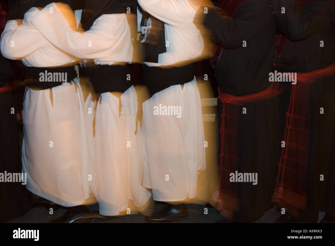 Hooded members of a religious fraternity wearing robes carry a float ...