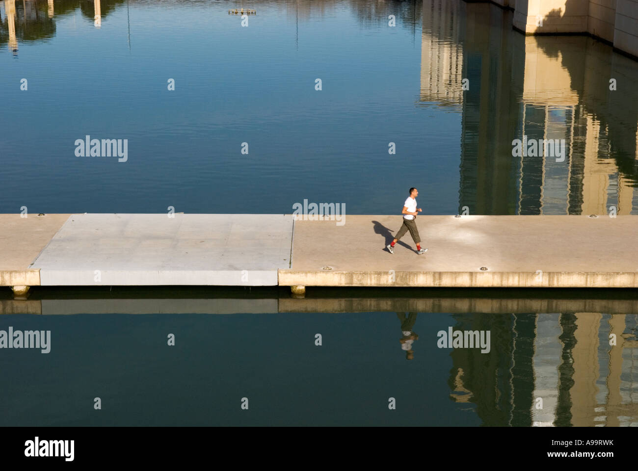 A male jogger jogs across a simple concrete bridge in the antigone quarter in montpellier, france Stock Photo