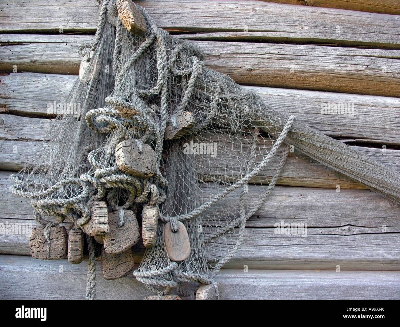 old fisher net on wall of a grey blockhouse house in open air museum Sagalund in Kemiö Kimito in Finland Stock Photo