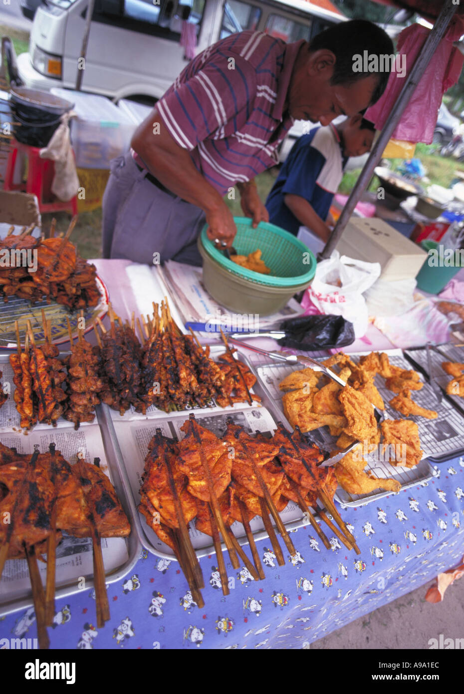 MALAYSIA Kedah Langkawi Cenang Night Market Food Stall Male vendor with various spicy grilled portions of chicken on skewers. Stock Photo