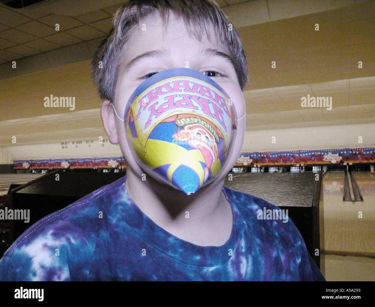 Eleven year old boy playing with paper hat at birthday party Stock