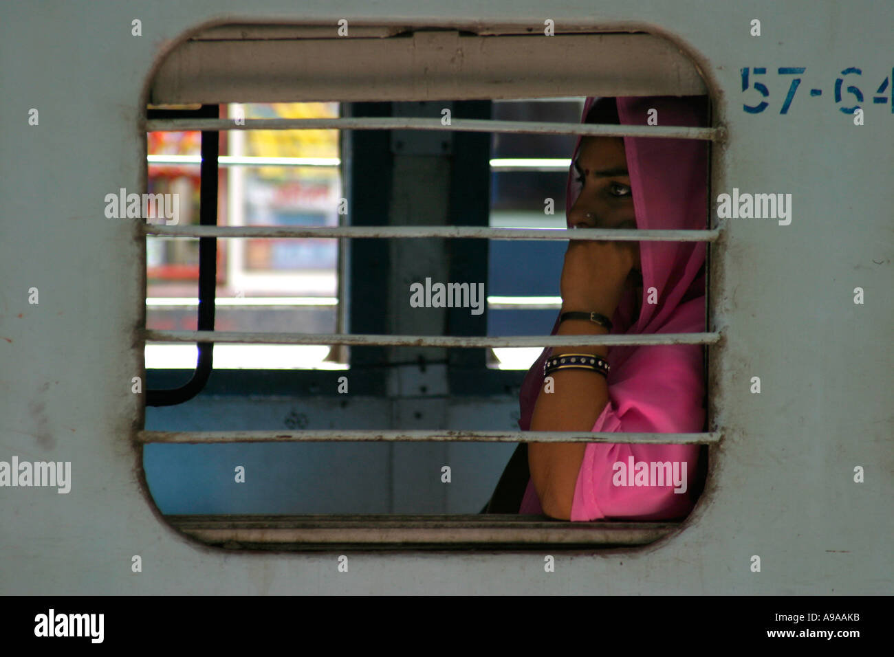 Female passenger in pink sari waits for train to depart. Jaipur Junction station, Rajasthan, India. Stock Photo