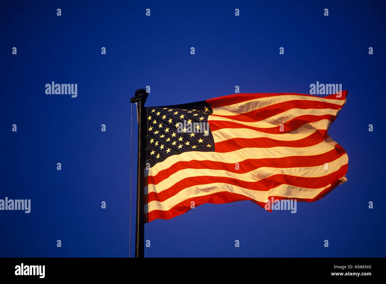 UNITED STATES FLAG FLYING ON FLAGPOLE WITH BLUE SKY Stock Photo - Alamy