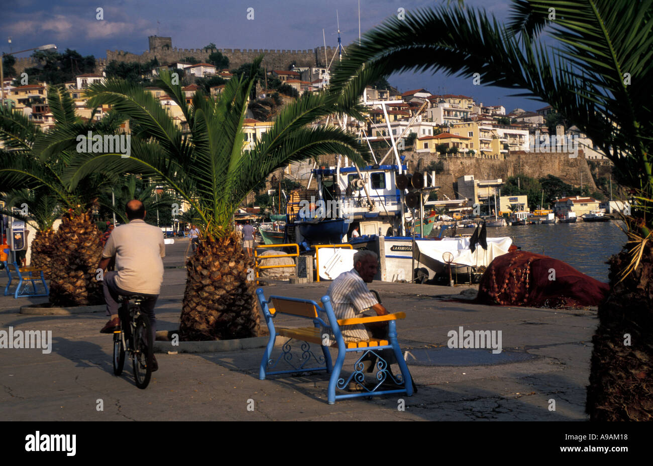 Man sits on bench in Evening Light watching life unfold Stock Photo
