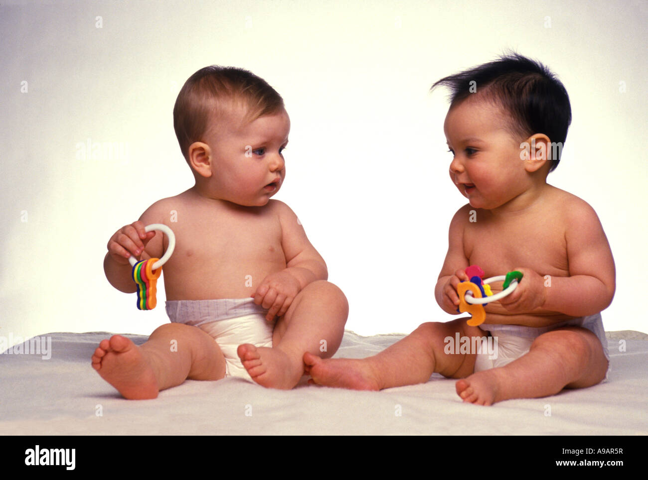 INFANT BABIES PLAYING WITH COLORED PLASTIC TOY KEYS Stock Photo