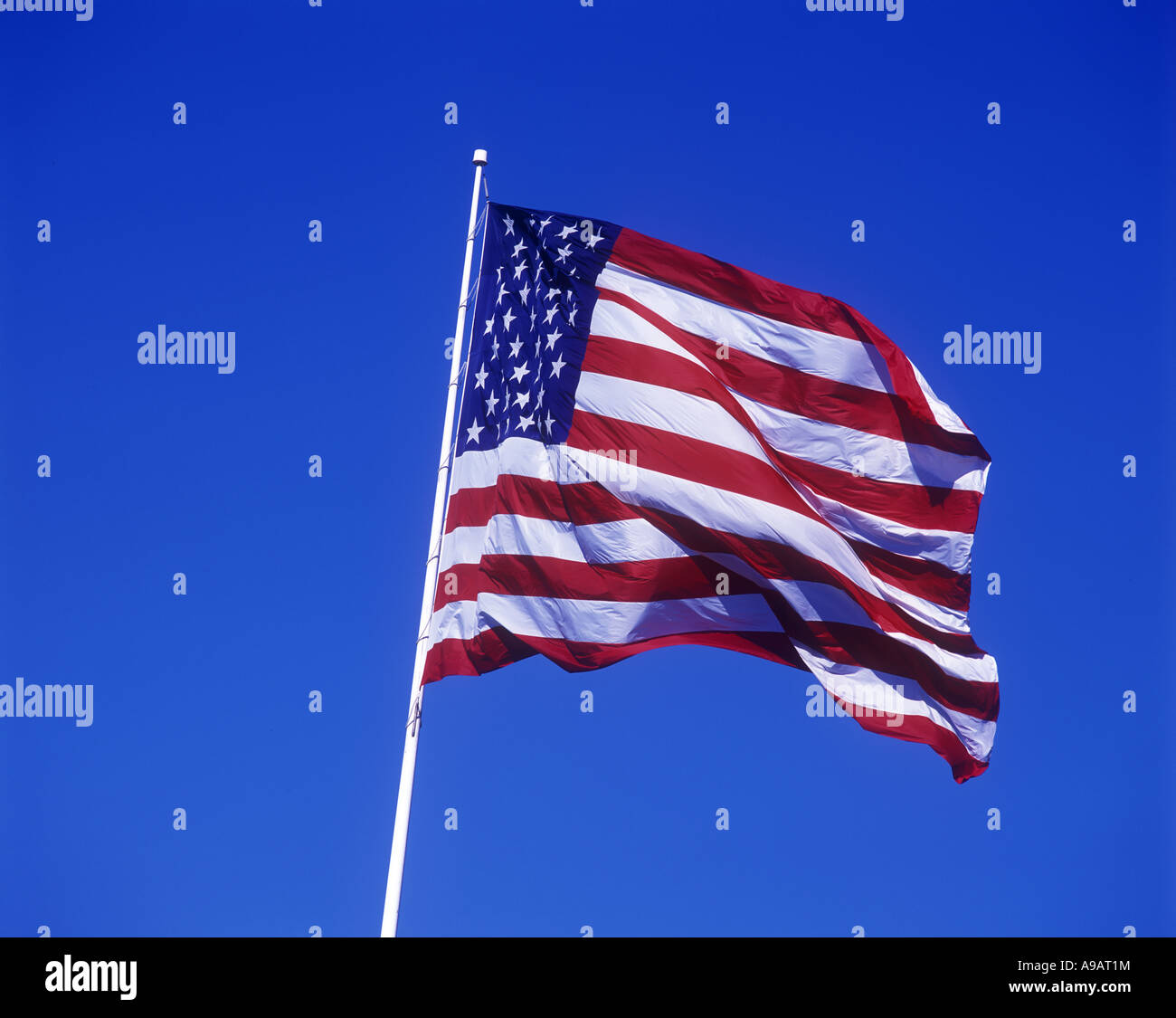 UNITED STATES FLAG FLYING ON FLAGPOLE WITH BLUE SKY Stock Photo - Alamy