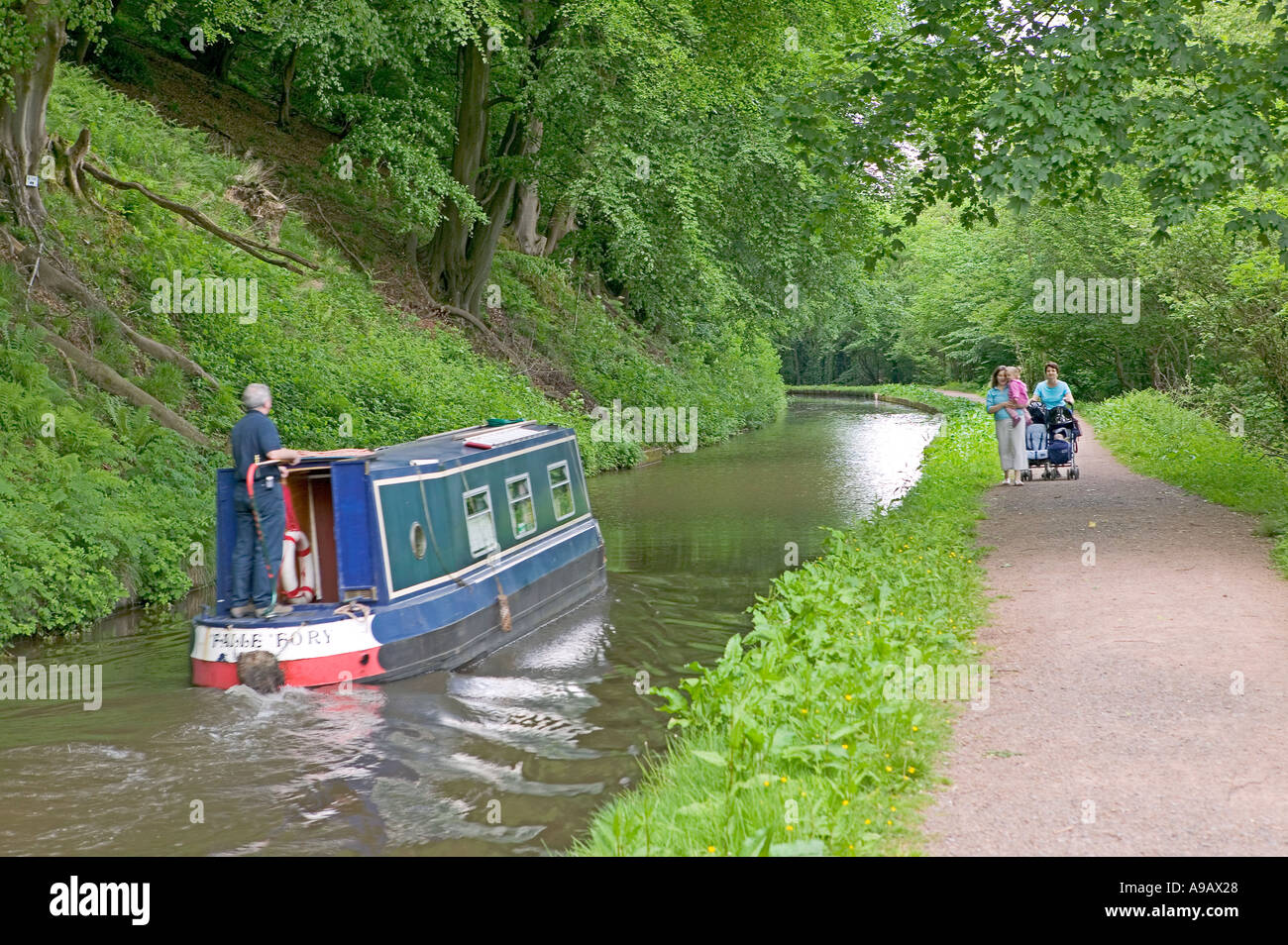 Canal boat on canal and towpath with pedestrians walking Brecon and Monmouth canal near Llanfoist South Wales UK Stock Photo