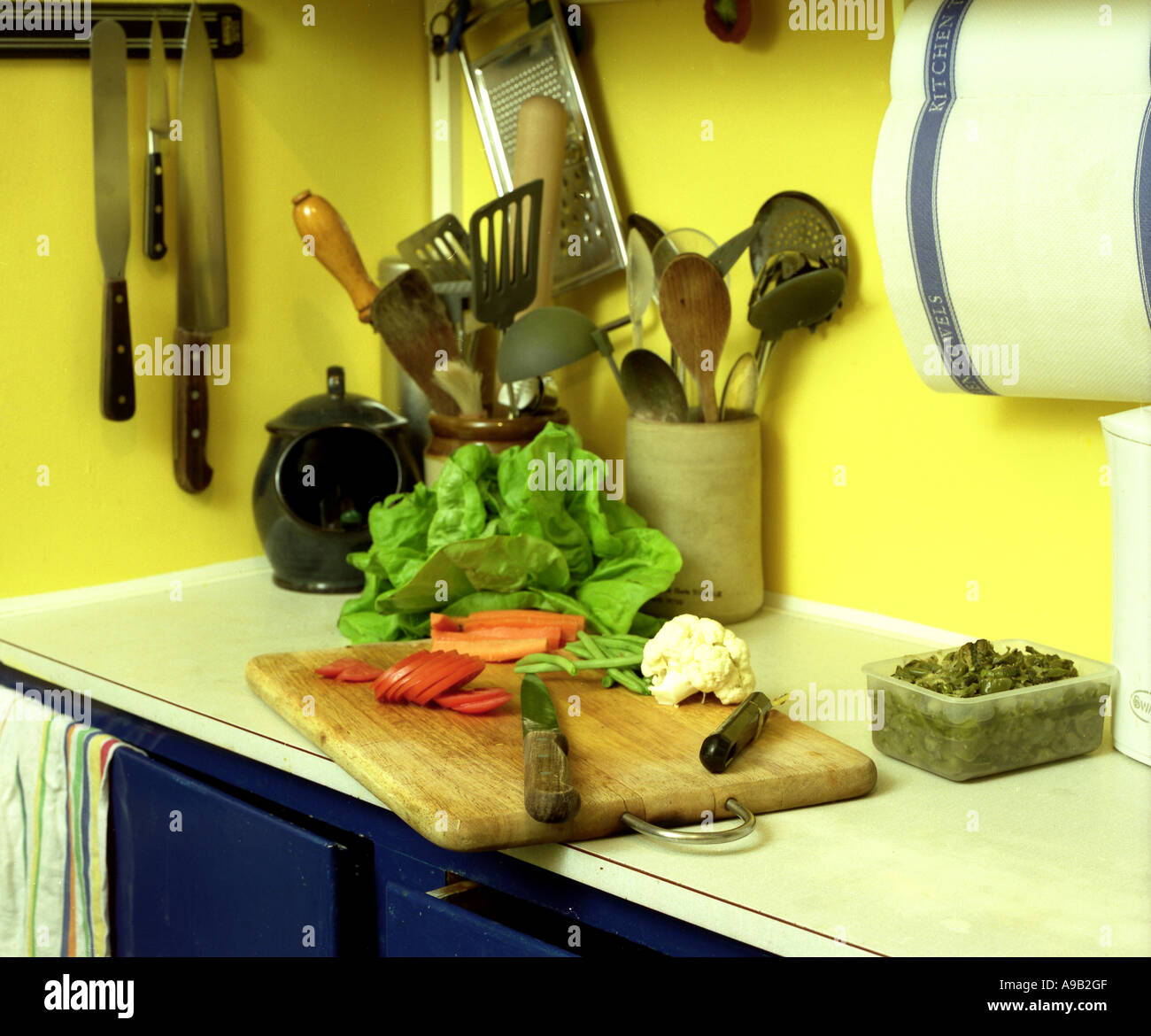 Kitchen scene with chopped tomatoes & salad, knives & various cooking ...