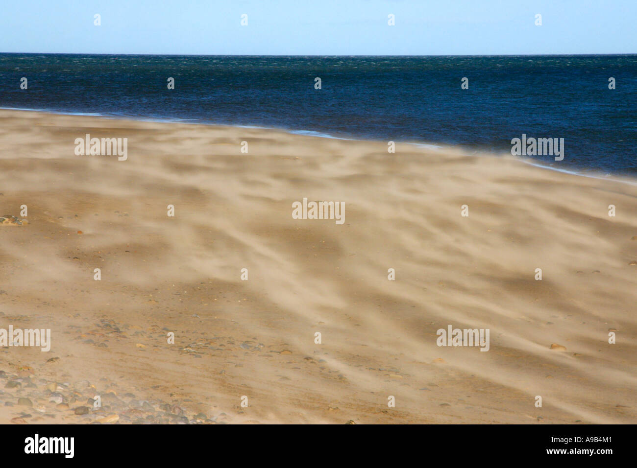 Sand being blown along a beach Stock Photo