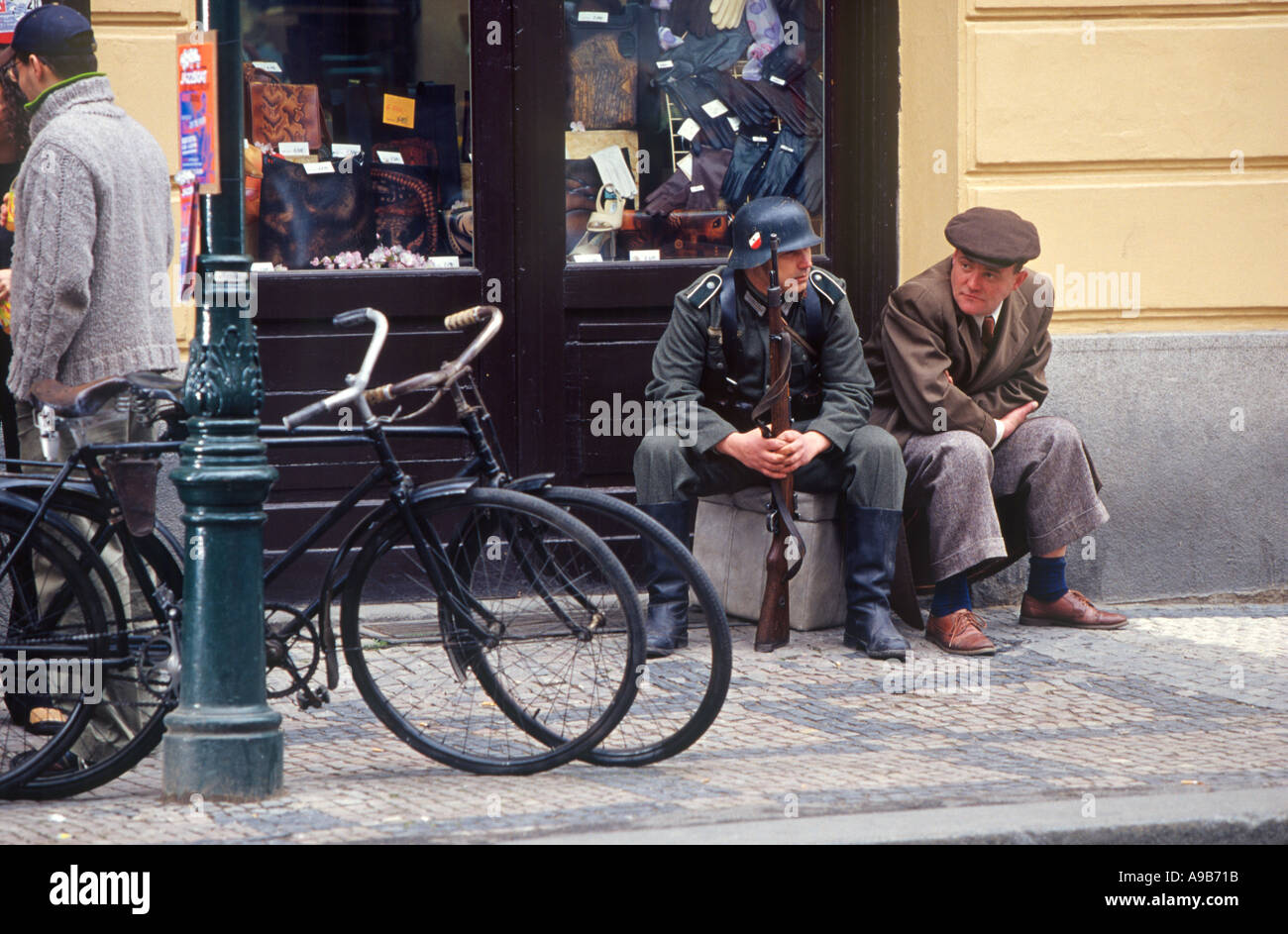 Actors in WWII costumes with old bicycles wait on the sidewalk as a movie is being made in Franz Kafka cafe Prague Stock Photo