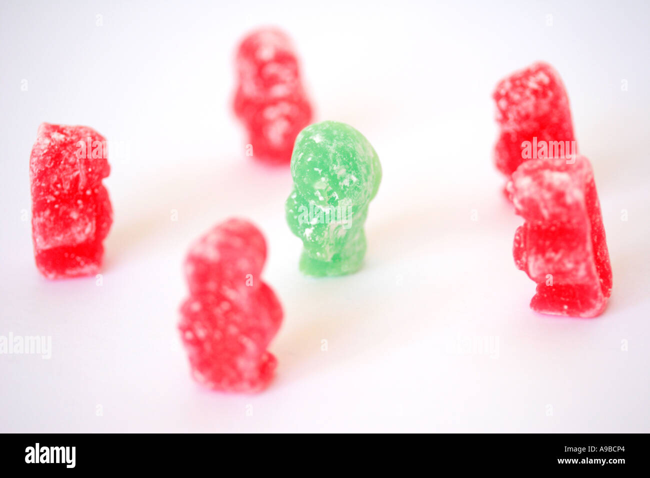 Green jelly baby amongst gang of pink jelly babies Stock Photo - Alamy
