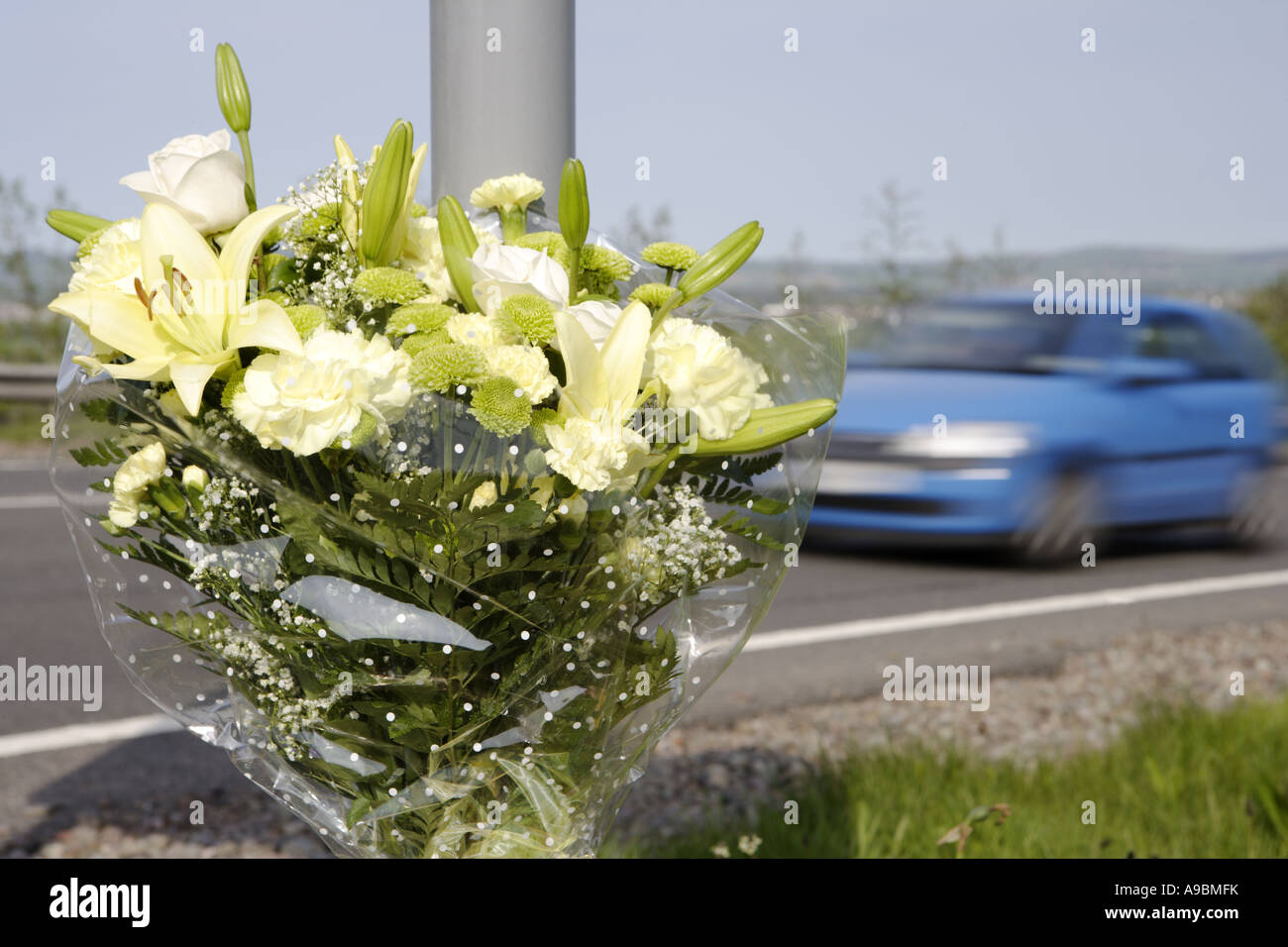 Death car speeding past a floral tribute marking the spot of a fatal road traffic accident Stock Photo