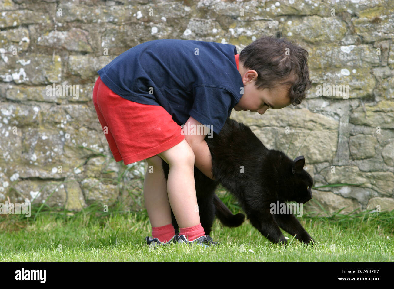 Small boy carrying his pet black cat Stock Photo