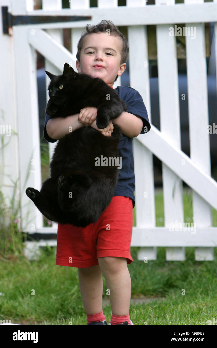 Small boy carrying his pet black cat Stock Photo
