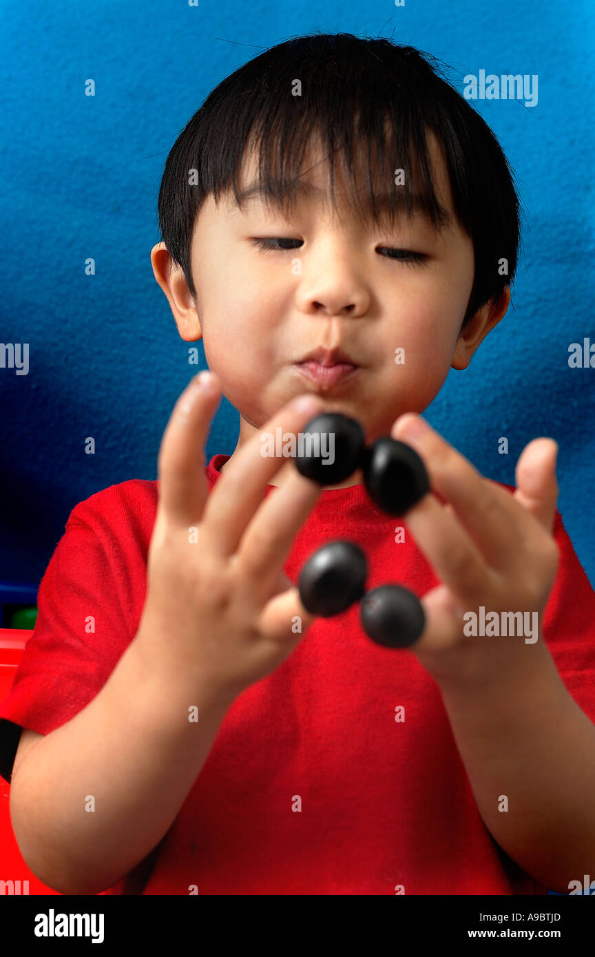 Boy with olives on fingers Stock Photo Alamy