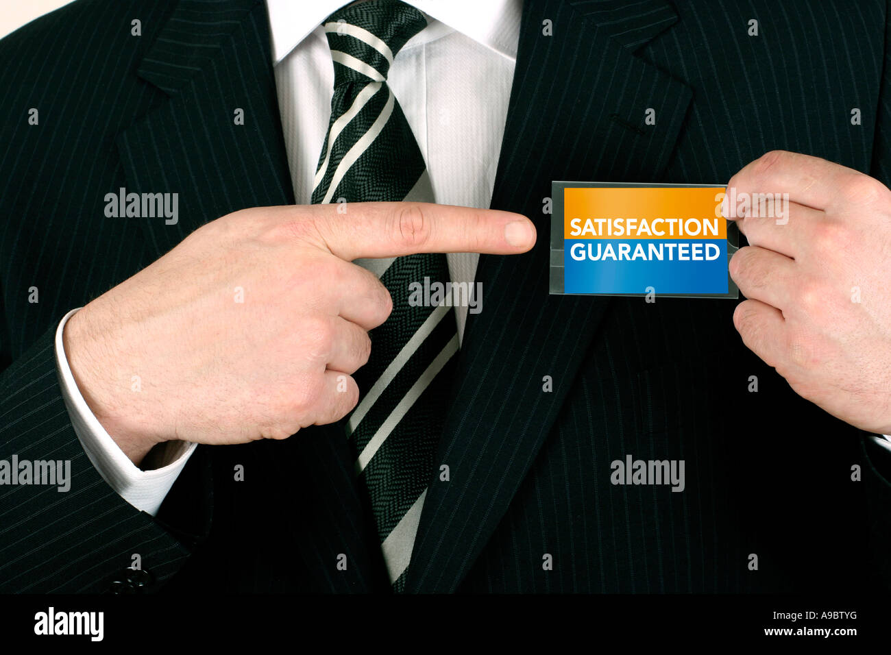 Business man making a sale pointing to a satisfaction guaranteed badge Stock Photo