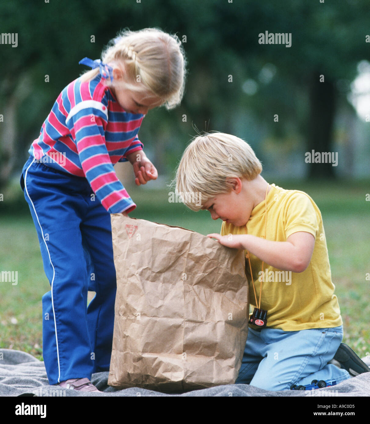 small boy and girl explore contents of a large paper bag Stock Photo