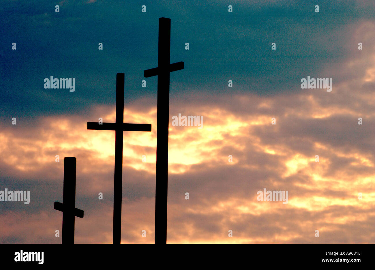 Horizontal color image of three crosses silhouetted against a vibrant ...