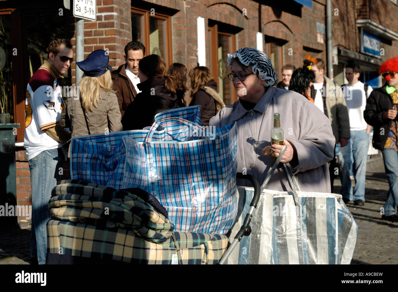 Carnival celebrations in Düsseldorf 2007. Woman collecting bottles with a pram. Stock Photo