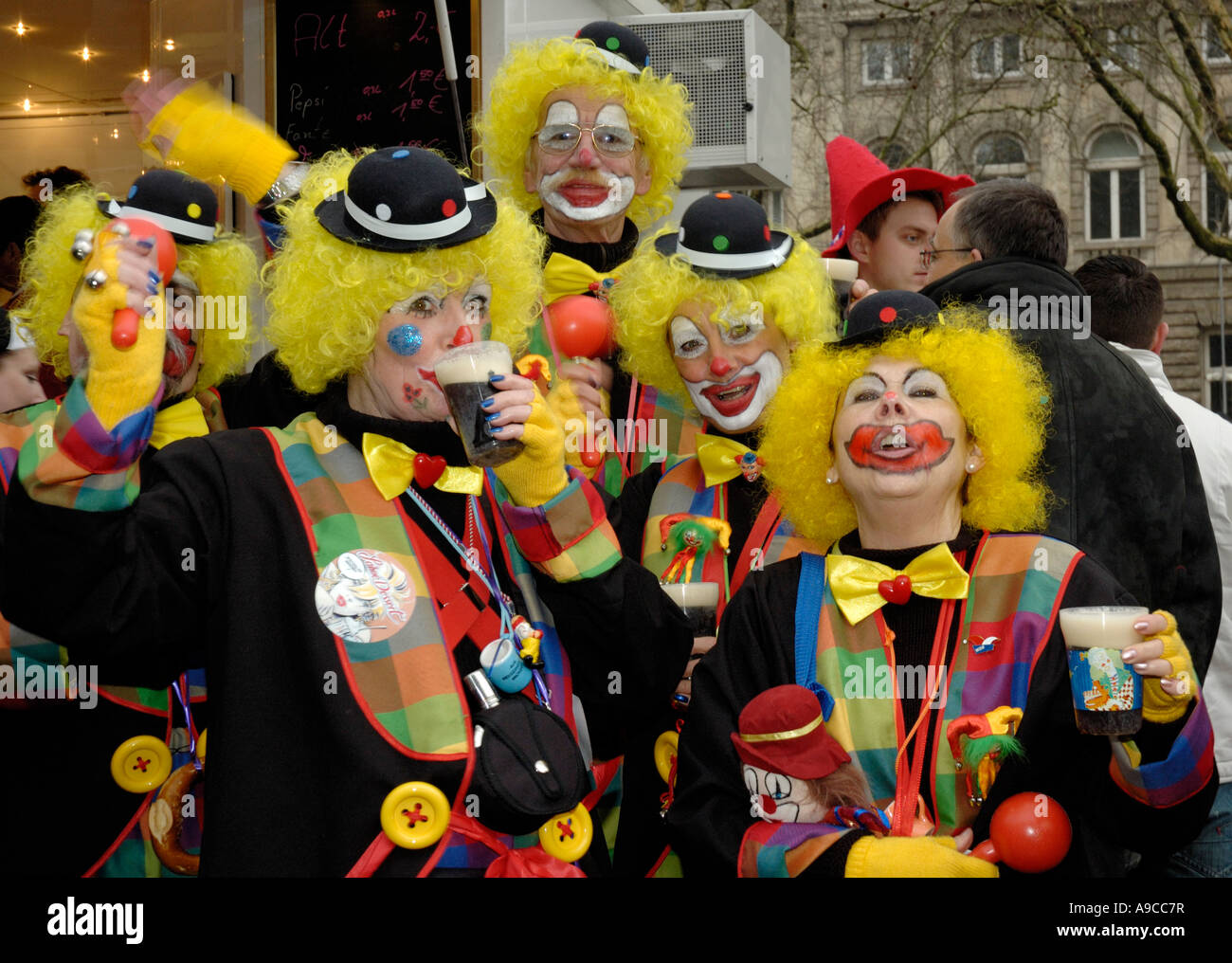 Group of 5 clowns with yellow wigs drinking alt beer and singing, Dusseldorf carnival 2007