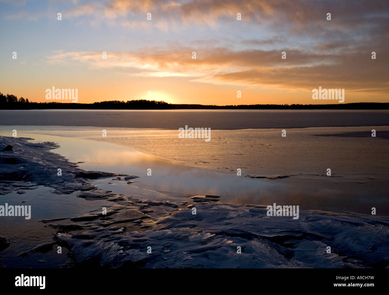 Last rays of sun reflecting from the fresh new ice skim layer on a lake ...