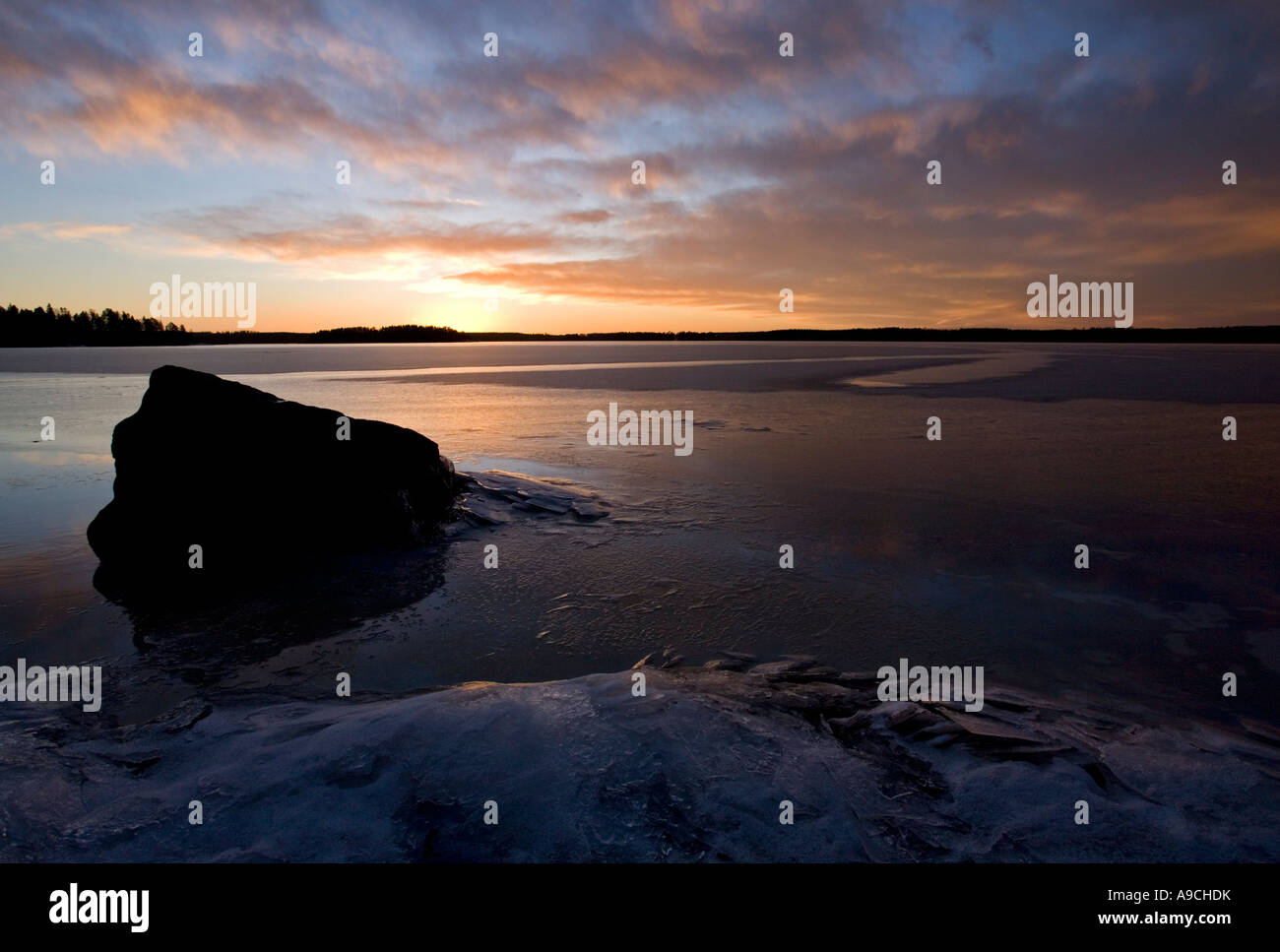 Last rays of sun reflecting from the fresh new ice skim layer on a lake ...