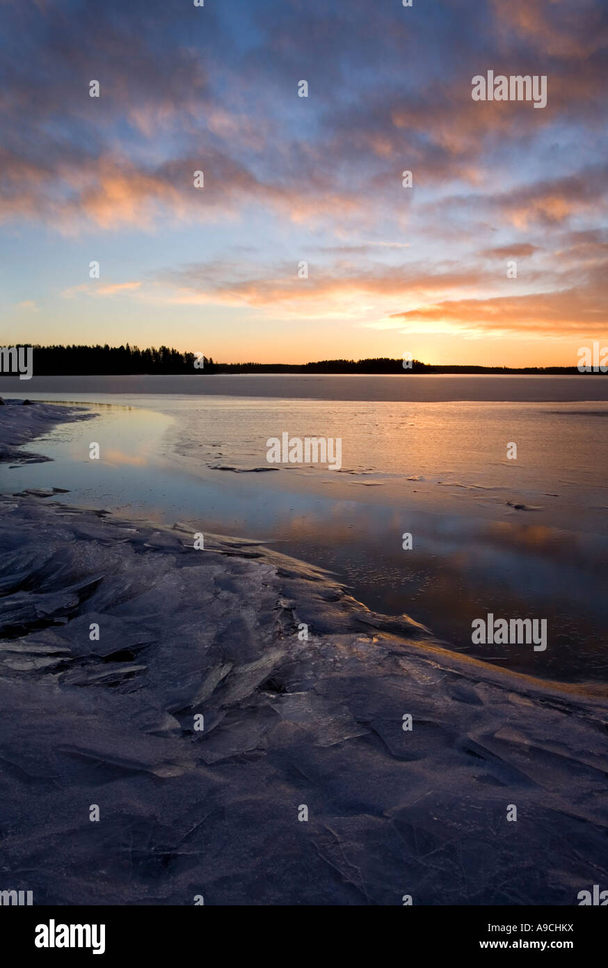 Last rays of sun reflecting from the fresh new ice skim layer on a lake ...