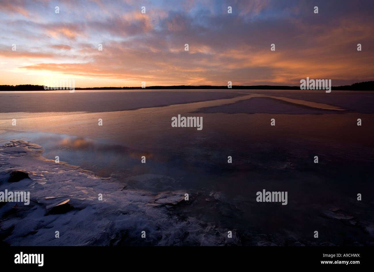 Last rays of sun reflecting from the fresh new ice skim layer on a lake ...