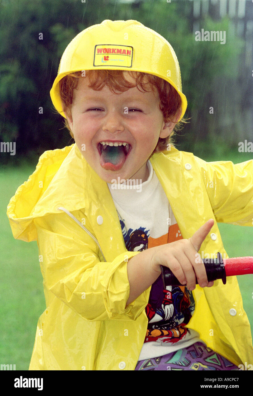 a young boy riding a bike in the rain wearing a yellow raincoat BAPN