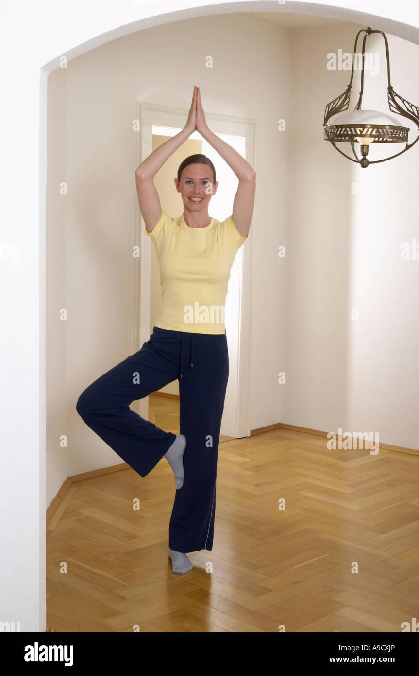 full body portrait of young woman doing yoga tree pose at home Stock ...