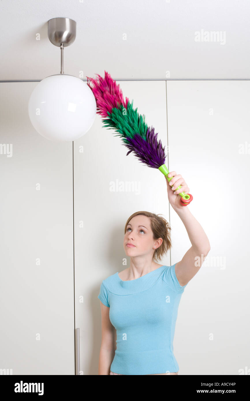 young woman dusting lamp with feather duster Stock Photo Alamy