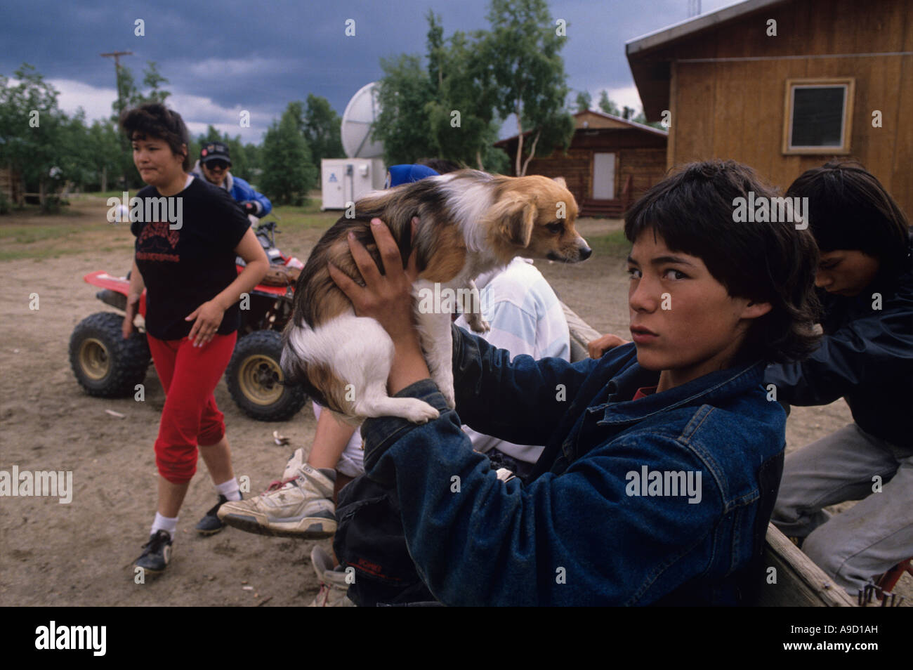 USA Alaska Athabascan Indian boy plays with puppy in village of Huslia