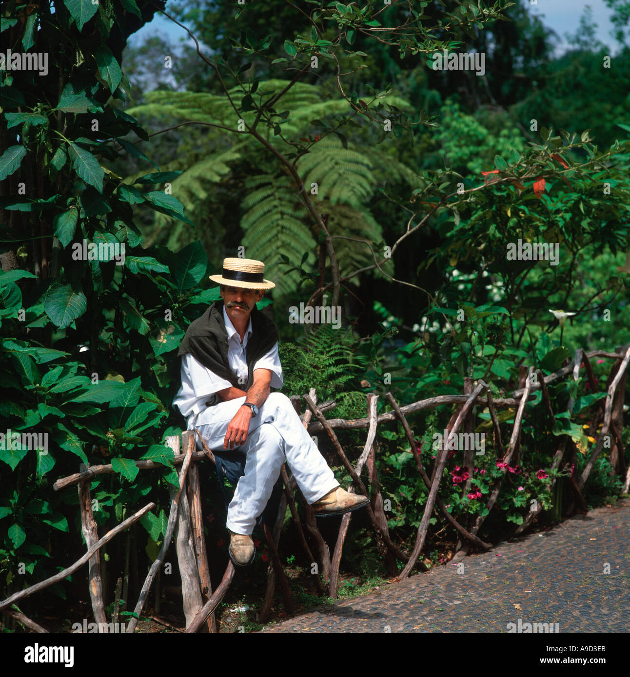 Toboggan driver sitting on a fence in Monte, near Funchal, Madeira, Portugal Stock Photo