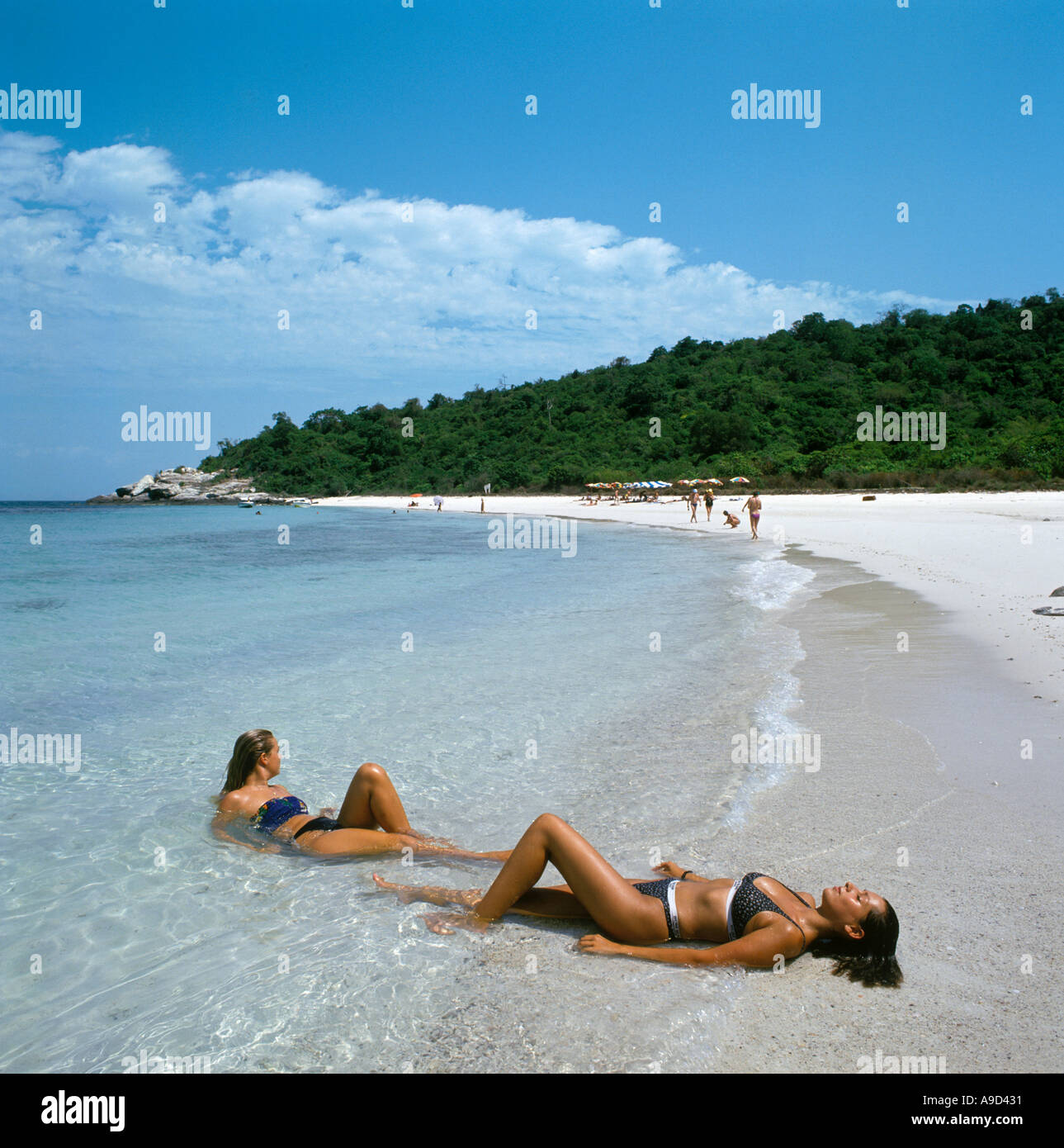 Two girls lying in the shallow water on the uninhabited island of Ko Phai (Bamboo Island) near Pattaya, Thailand Stock Photo