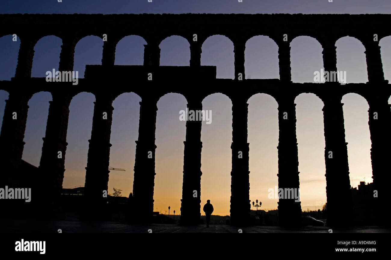 A man passes in front of Segovia 2000 year old Roman aqueduct at dawn in Segovia central Spain Stock Photo