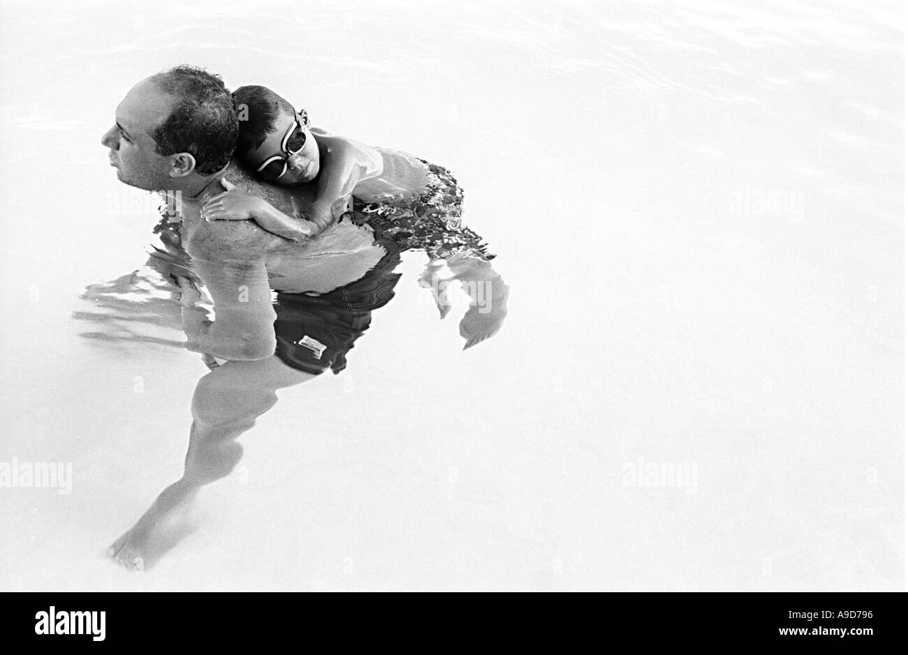 a boy embraces his father in a pool Stock Photo