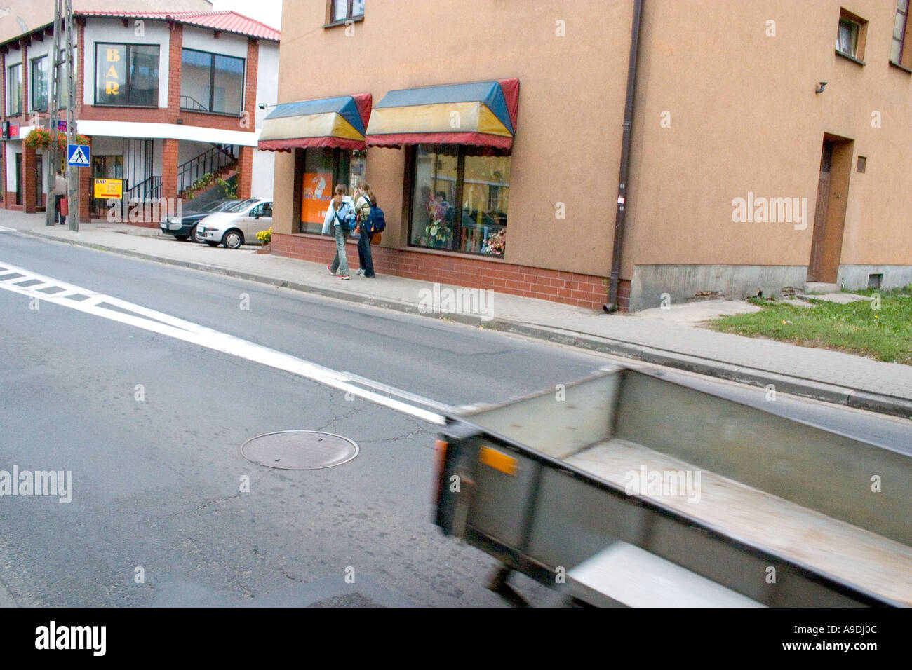 Teens with backpacks walking by some shops. Rawa Mazowiecka Poland Stock Photo