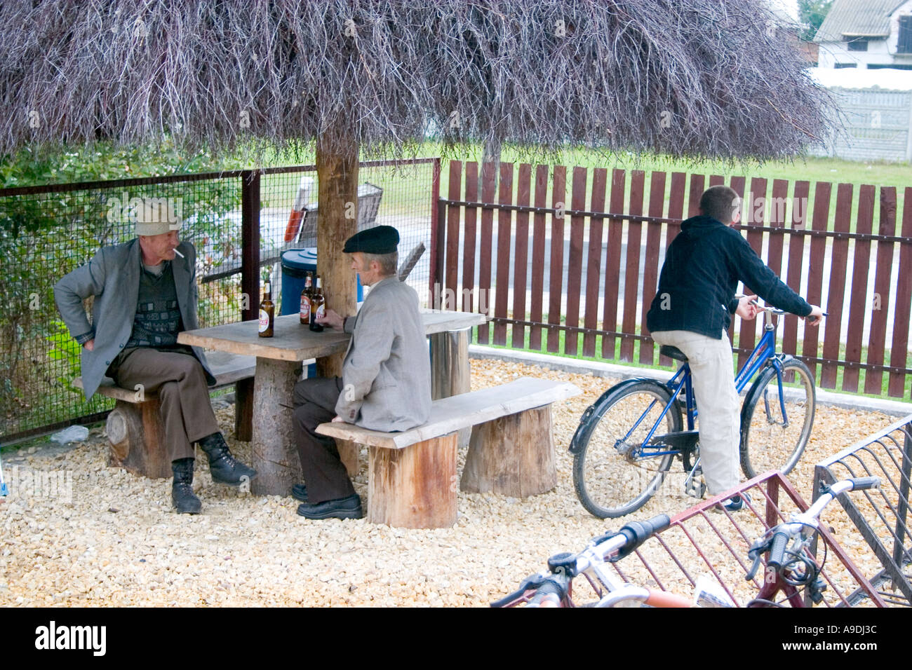 Men talking, smoking and drinking beer in grocery store courtyard. Sadykierz Poland Stock Photo