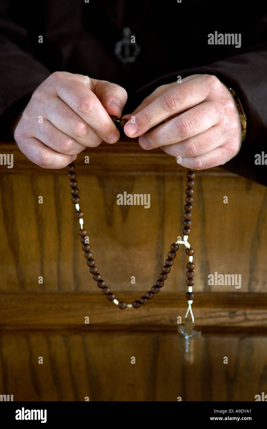 Hands of a roman catholic monk holding a rosary during prayer Stock Photo