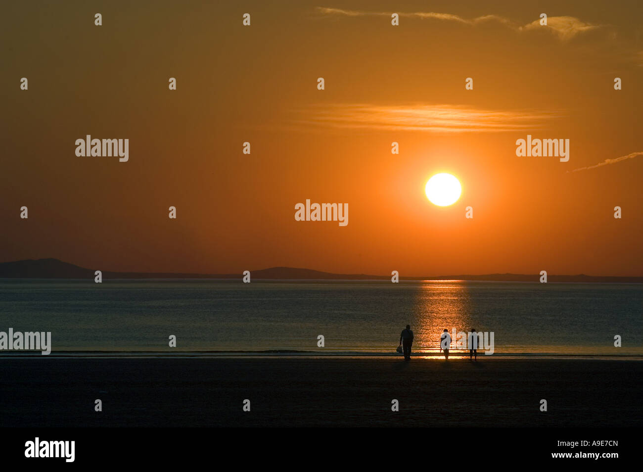 Family on beach at Broadhaven at sunset Pembrokeshire Dyfed West Wales ...