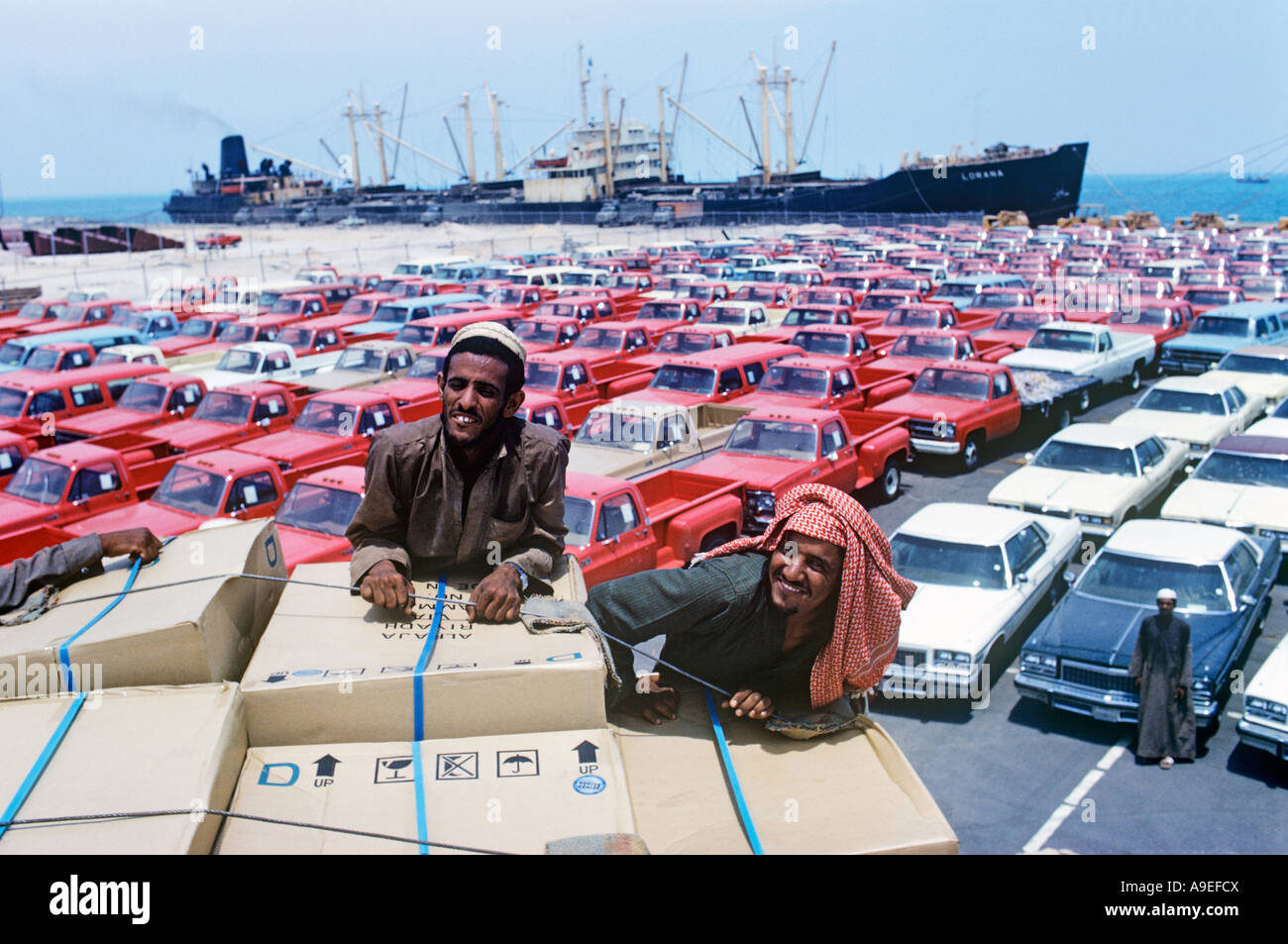 Saudi Arabia,Dammam port. Against a background of cars for and the ship that delivered them. Palestinan labourers pose happily. Stock Photo