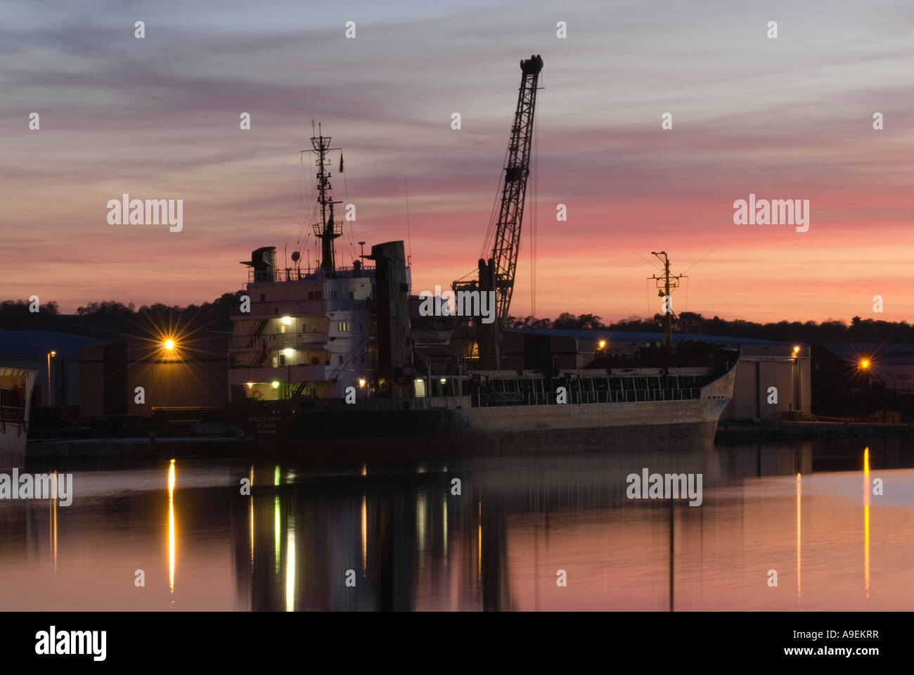 Birkenhead docks with ship and cranes silhouetted against sunset near Wallasey Merseyside North West UK Stock Photo