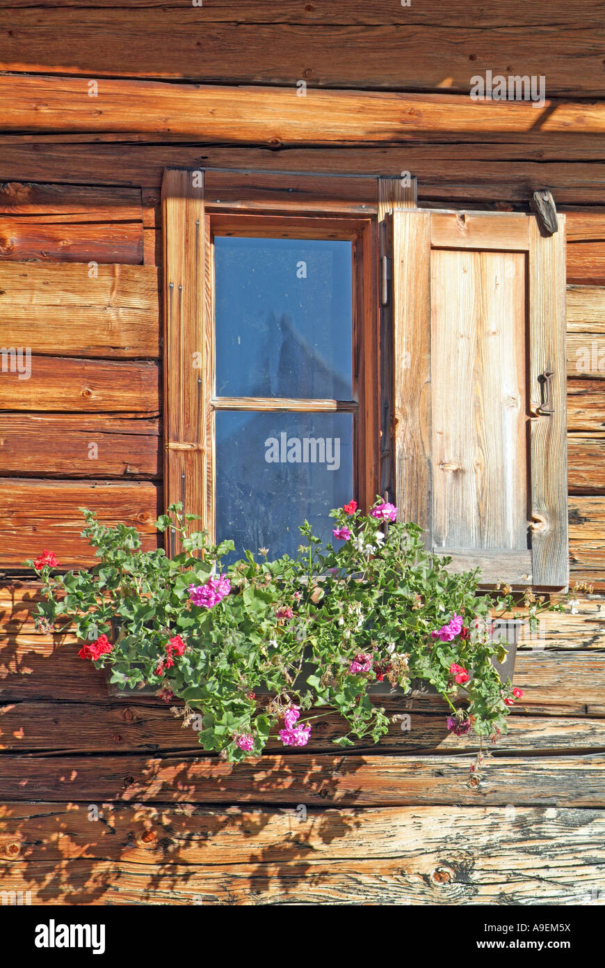 Window of a wooden alpine house decorated with Geraniums Stock Photo