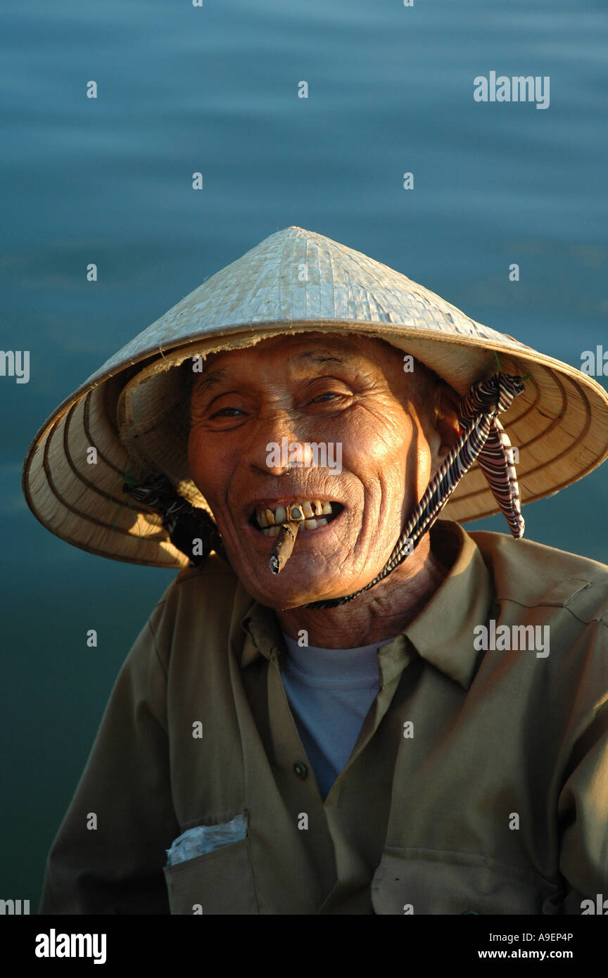 A boatman enjoys a hand rolled cigar on the Thu Bon River, Hoi An, Vietnam. Stock Photo