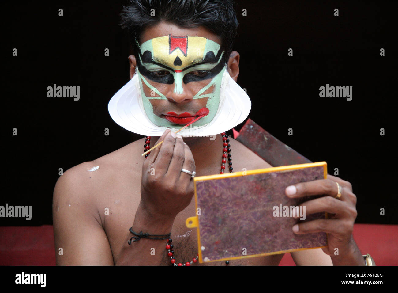 A Kathakali artist (Mattbaier) paints his face in vividly coloured make-up for a show in Varkala, Kerala, South India Stock Photo