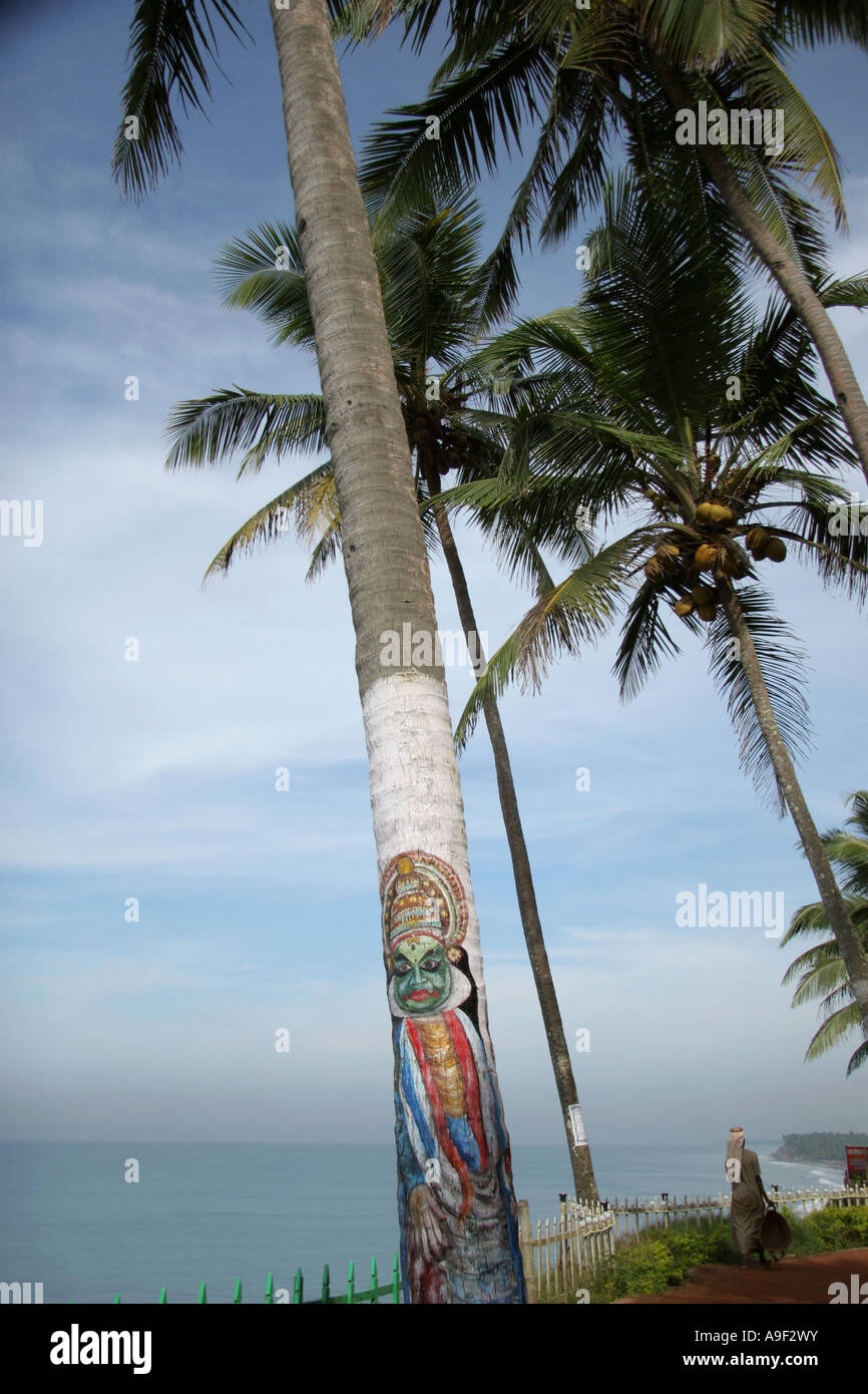 A palm tree is painted with a typical face of a Kathakali performer on the cliff top path in Varkala, Kerala, South India Stock Photo