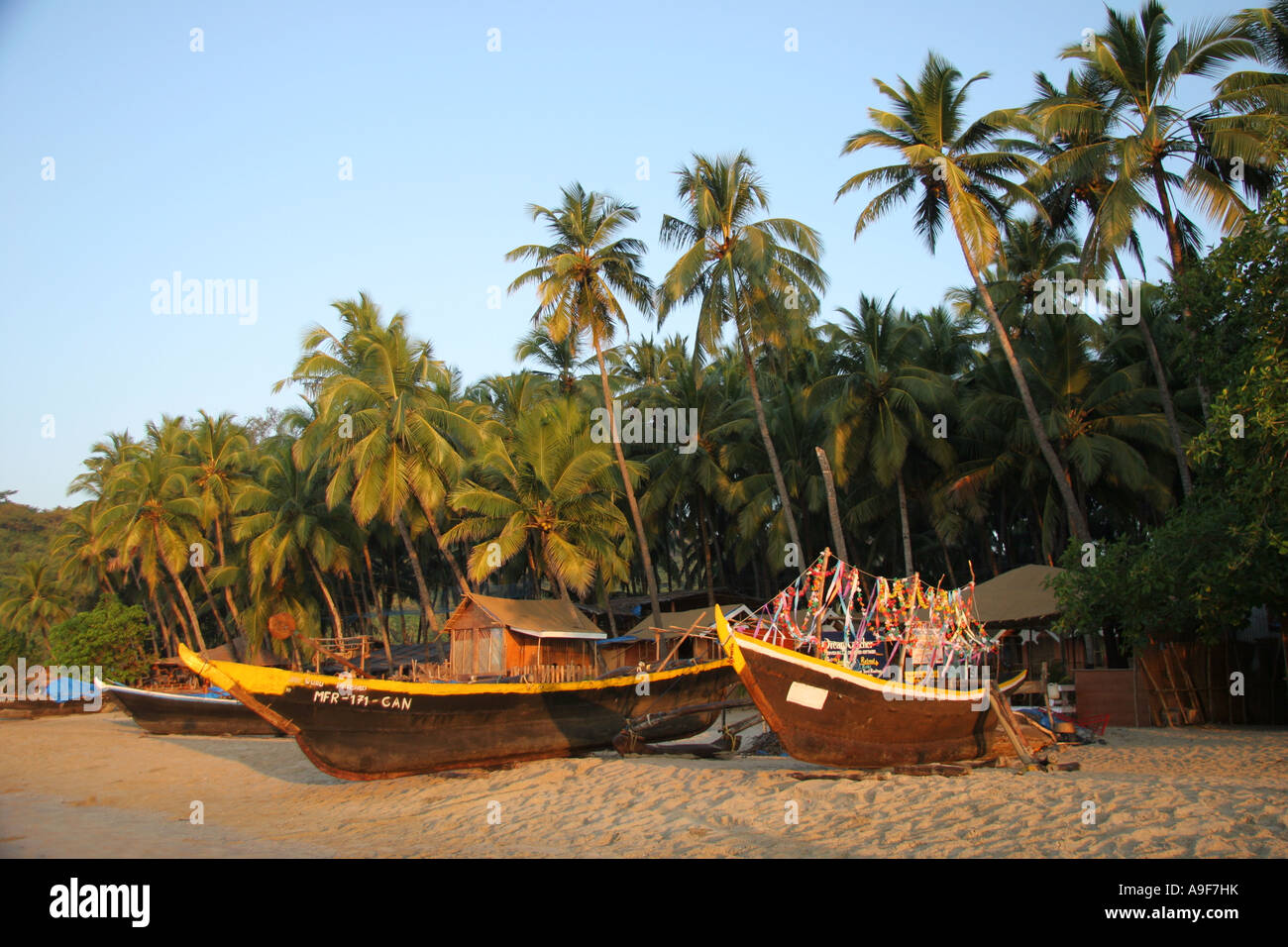 Fishermens boats, one decorated with flower garlands on the beach in Palolem in Southern Goa, India Stock Photo